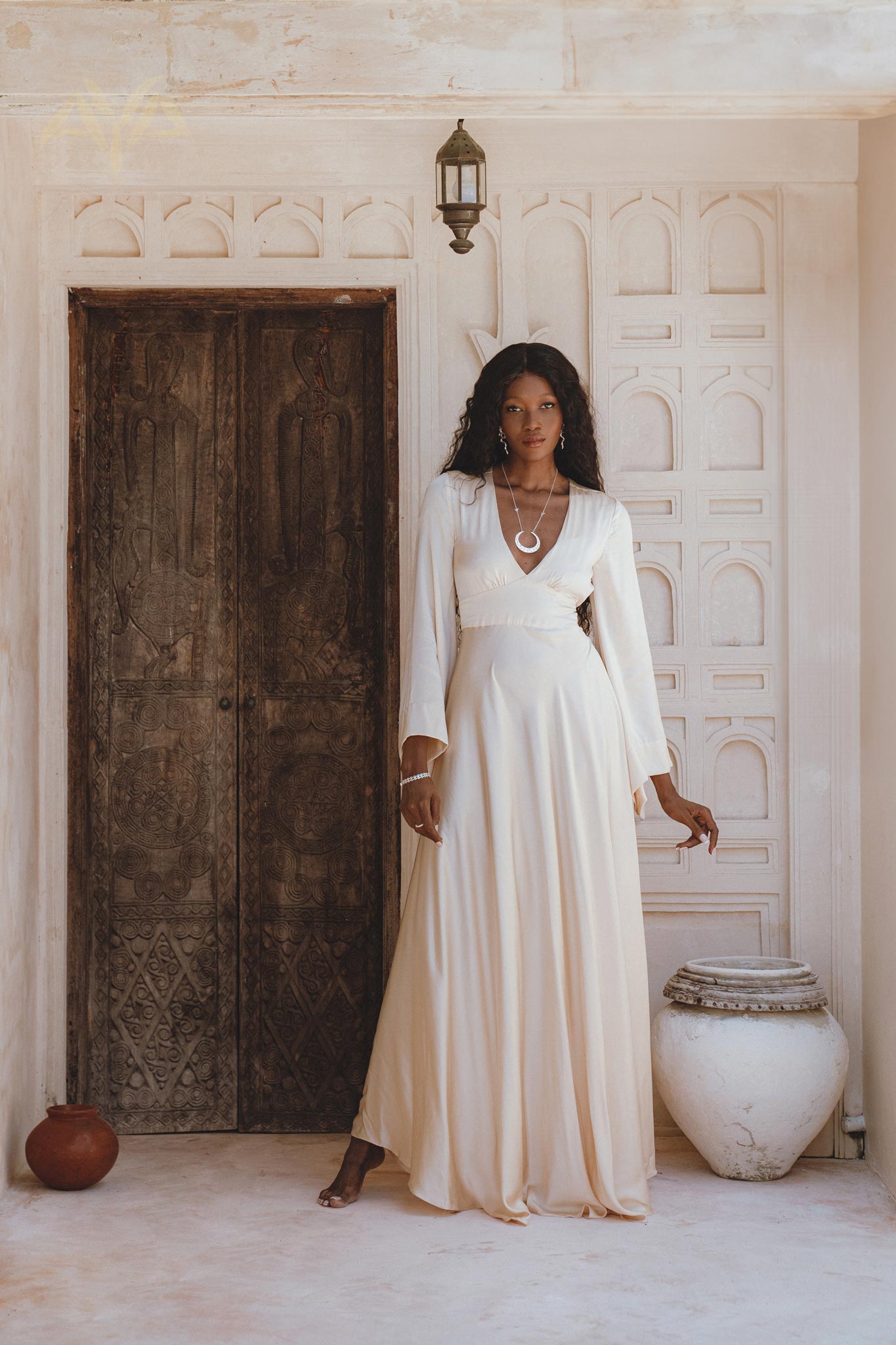 Stunning off-white silk bridal dress with a bohemian goddess vibe, featuring an open back and flowing bell sleeves.
