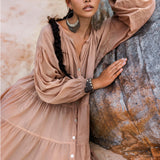 Against a rocky backdrop, a person with long braided hair poses outdoors wearing AYA Sacred Wear's Boho Dress for Women in dusty pink, paired with large circular earrings. The soft cotton fabric and natural surroundings create a serene, bohemian ambiance.